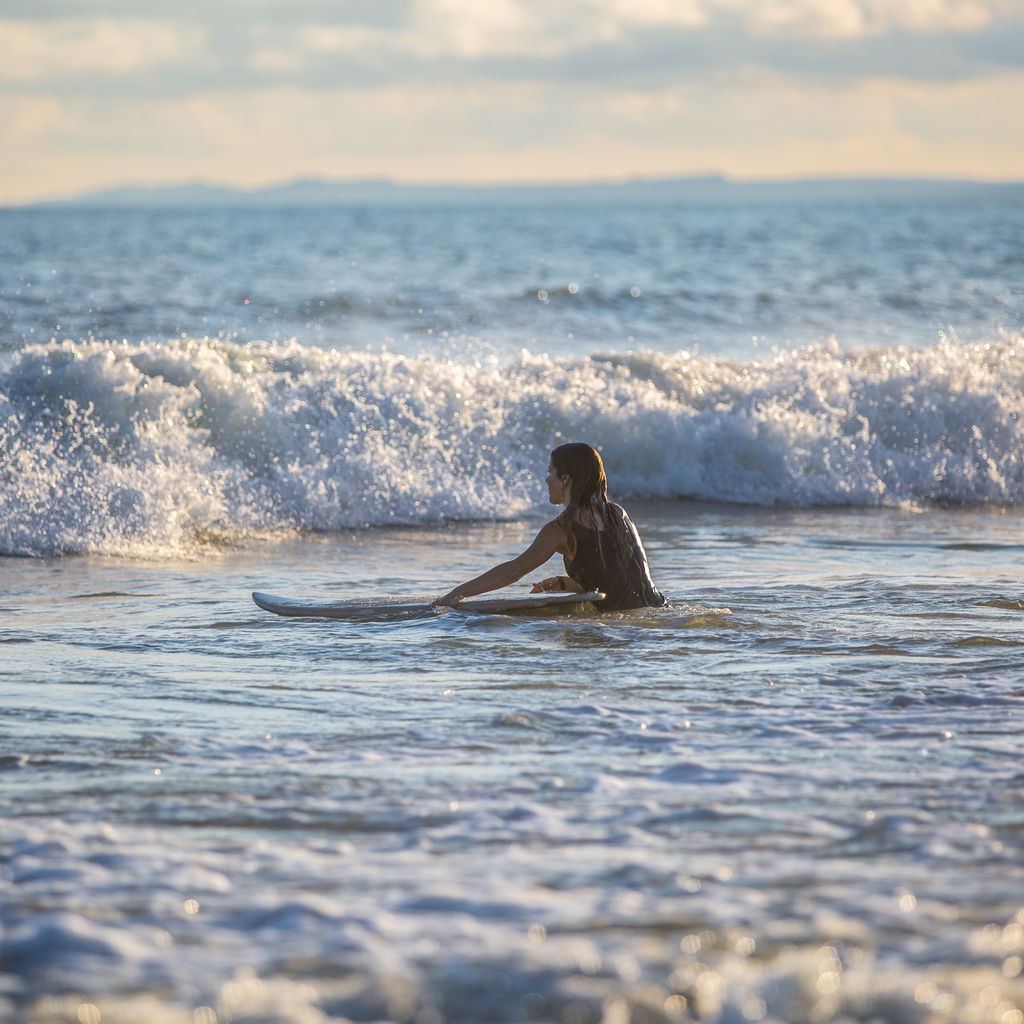 Woman with surfboard sea against sky
