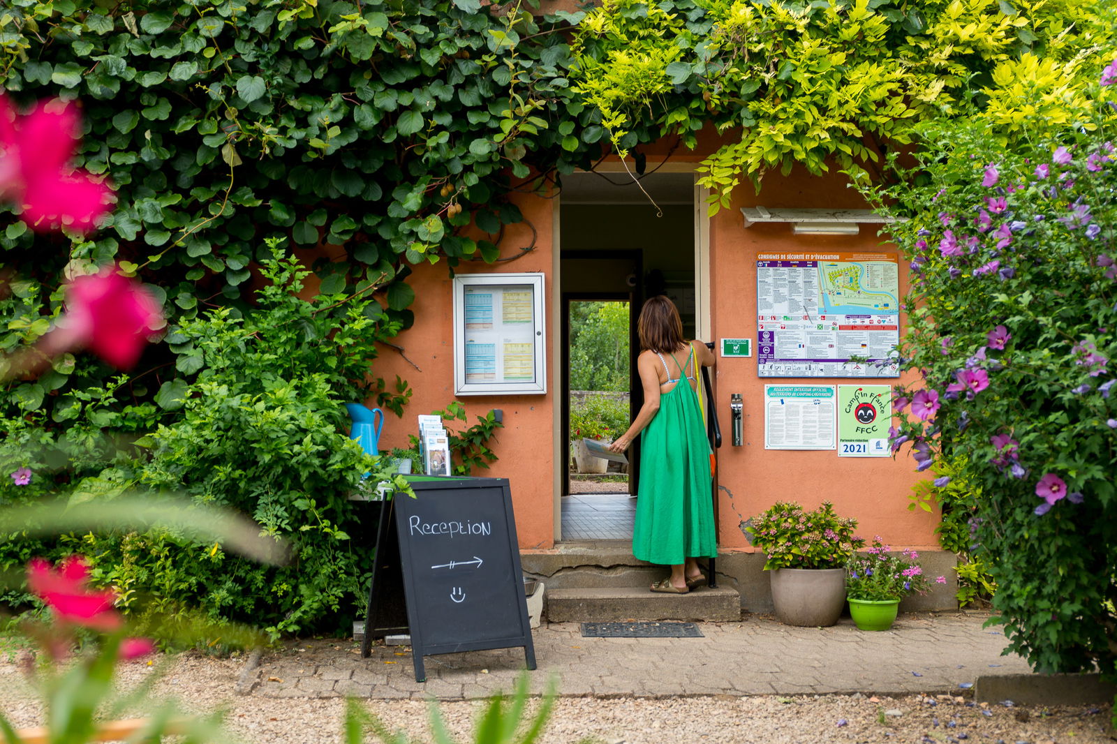 Vrouw in groene jurk loopt een receptie binnen op een camping