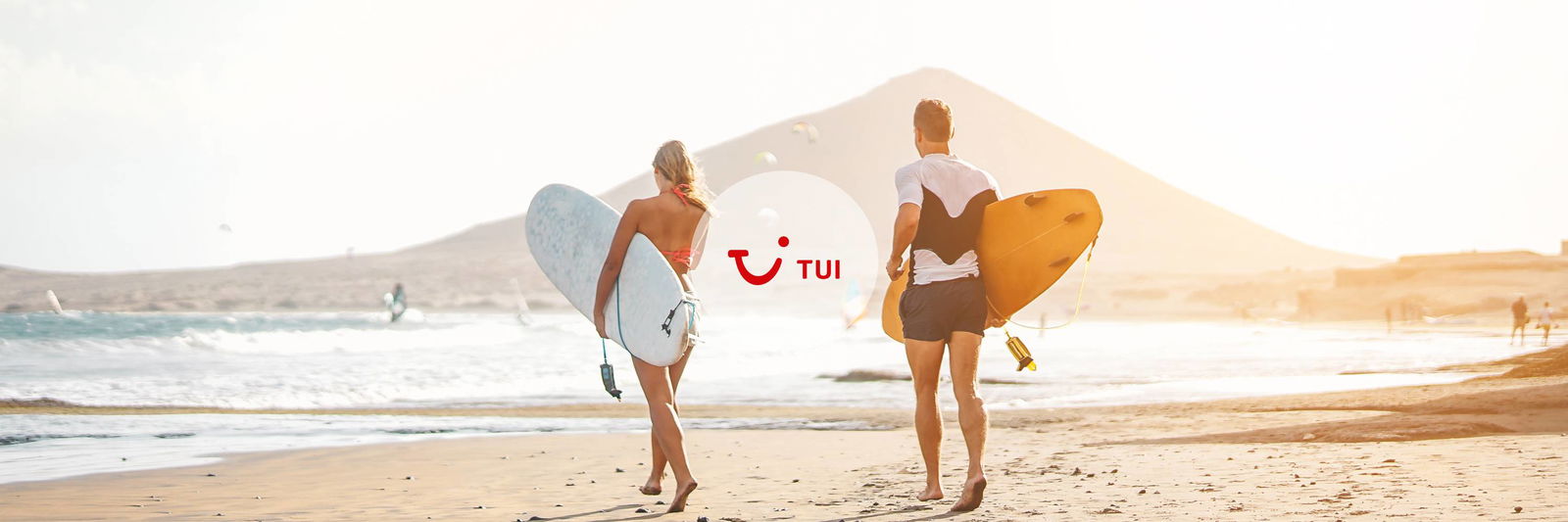 Men and woman walk on the beach with surfboard