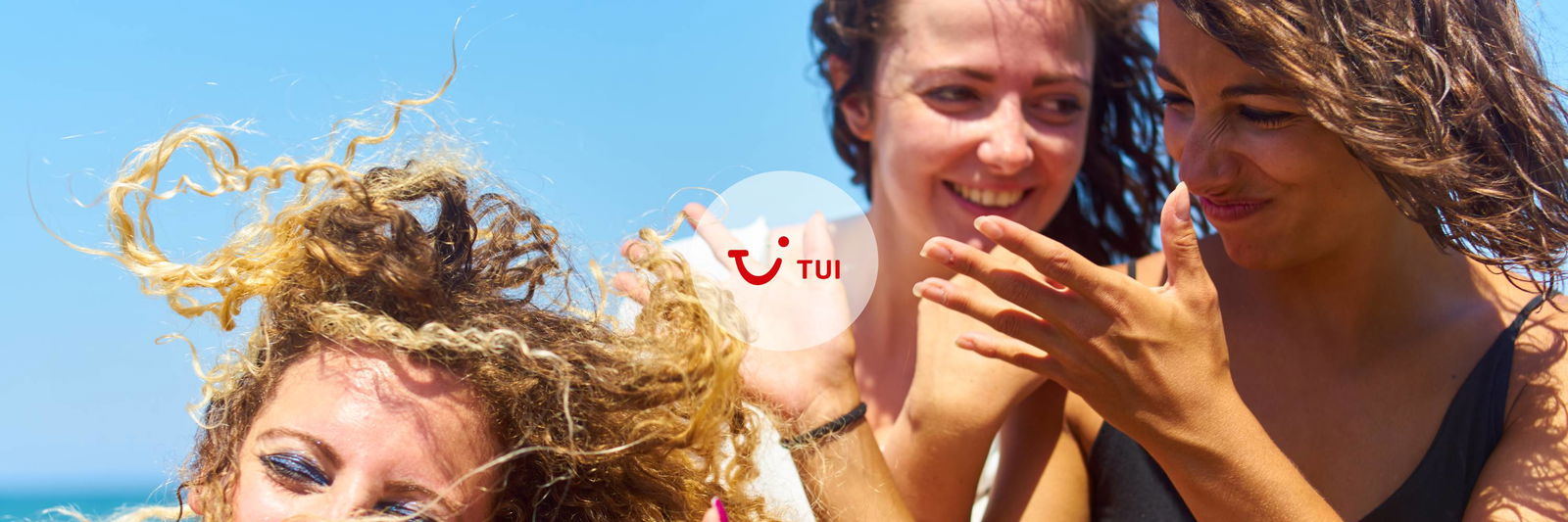 Drei fröhliche Frauen lachen sich an einem sommerlichen Tag an.