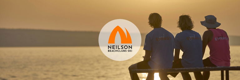 Drie medewerkers van een strandresort kijken naar de zonsondergang