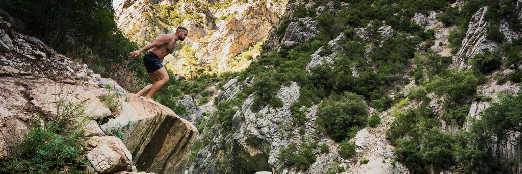 young man with athletic build prepares jump into water from cliff lake verdon