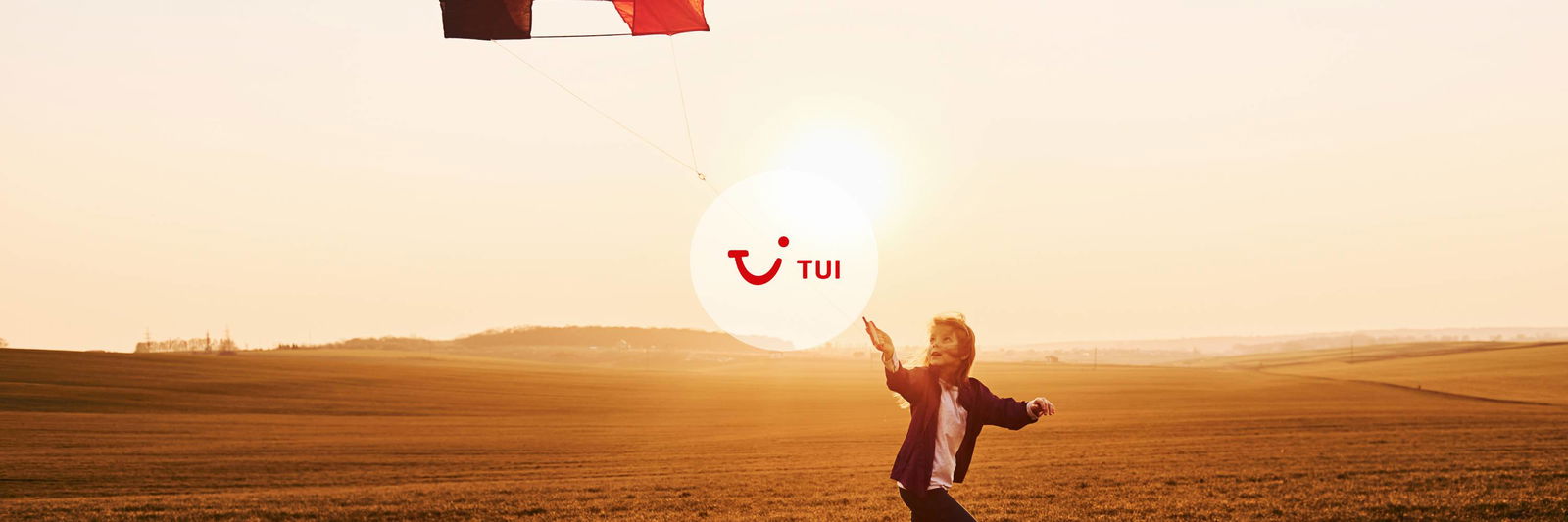 Kind loopt met een vlieger door een veld met een vlieger