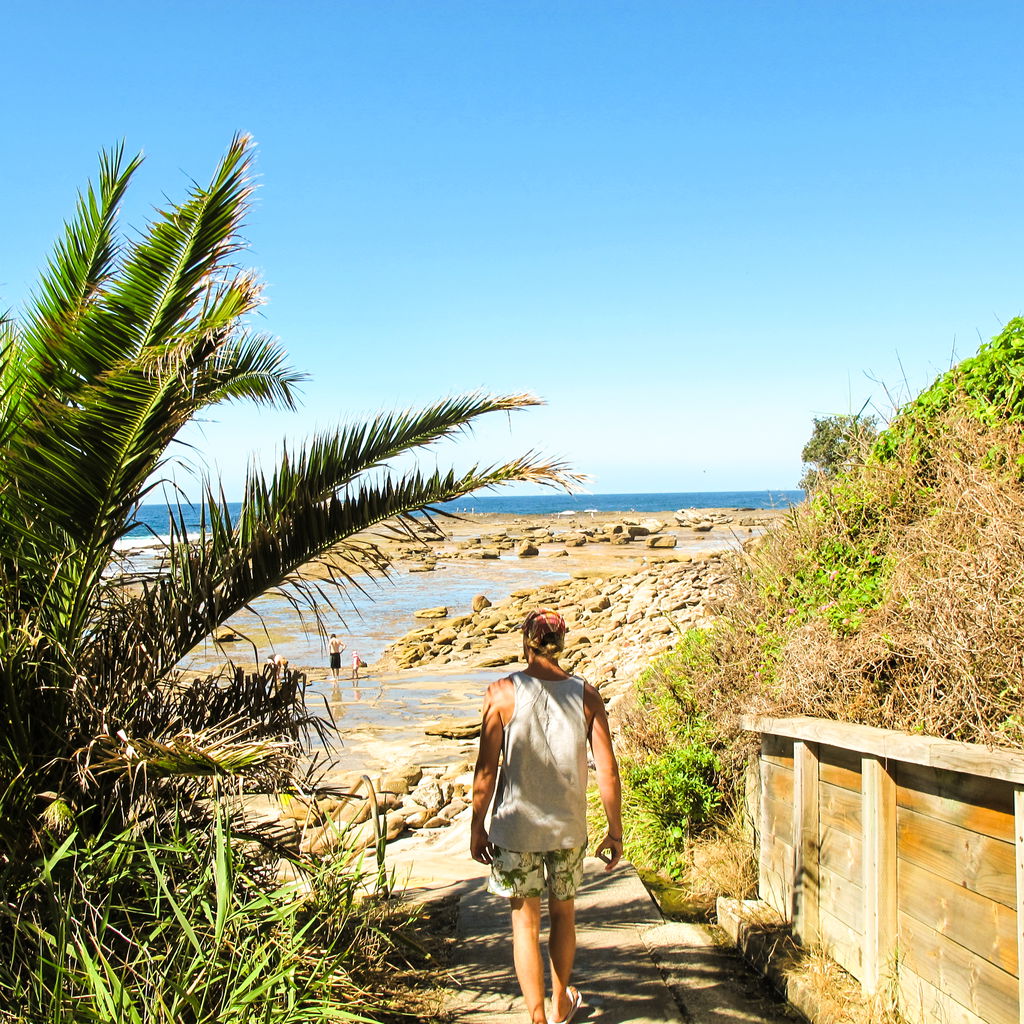 Rear view man walking towards beach against sky