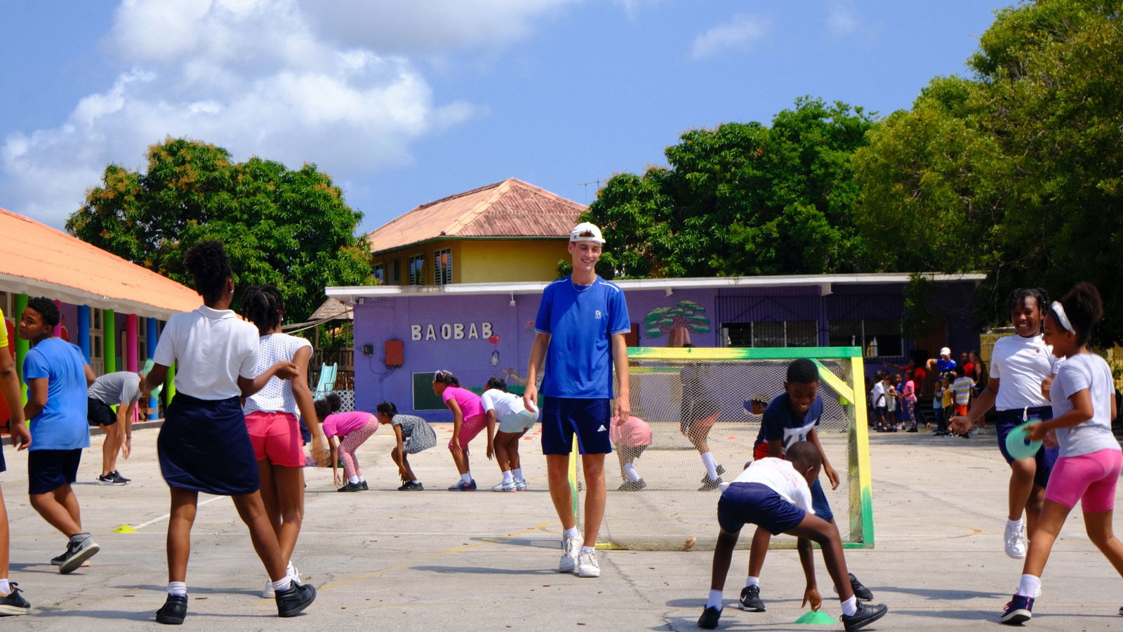 Volunteer on a soccer field with children playing