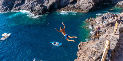 Man duikt in het water vanaf een rots op de Canarische Eilanden