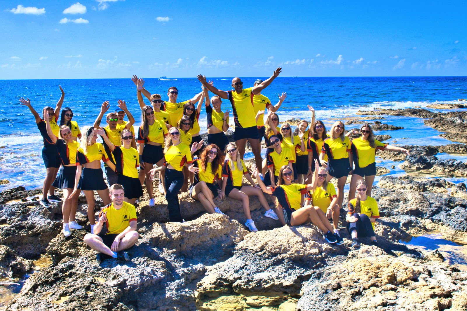 Teamfoto von Entertainern mit dem Meer im Hintergrund