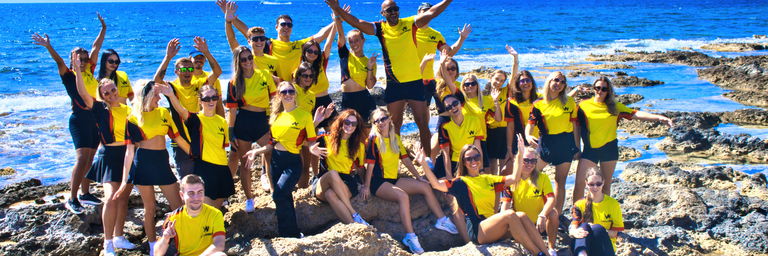 Teamfoto von Entertainern mit dem Meer im Hintergrund