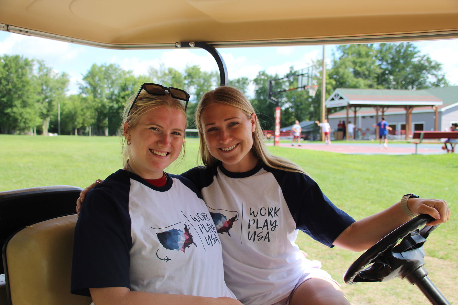 Two girls in a golf car at a summer camp