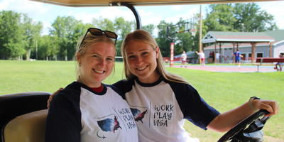 Twee meiden in een golfcar op een summercamp