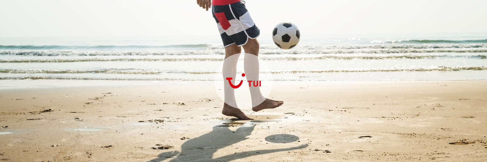 Man aan het voetballen op het strand